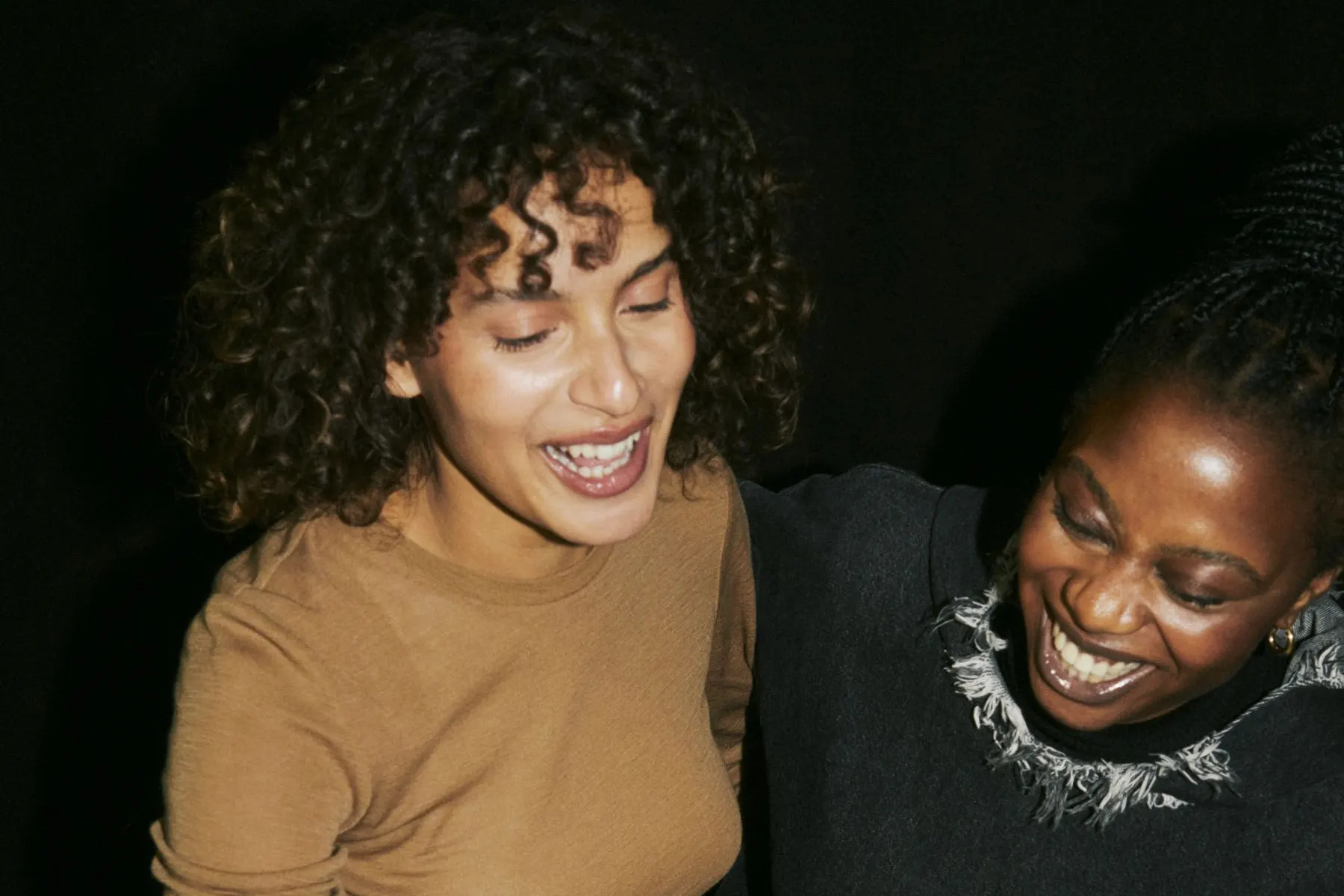 Two women laughing together, leaning in close