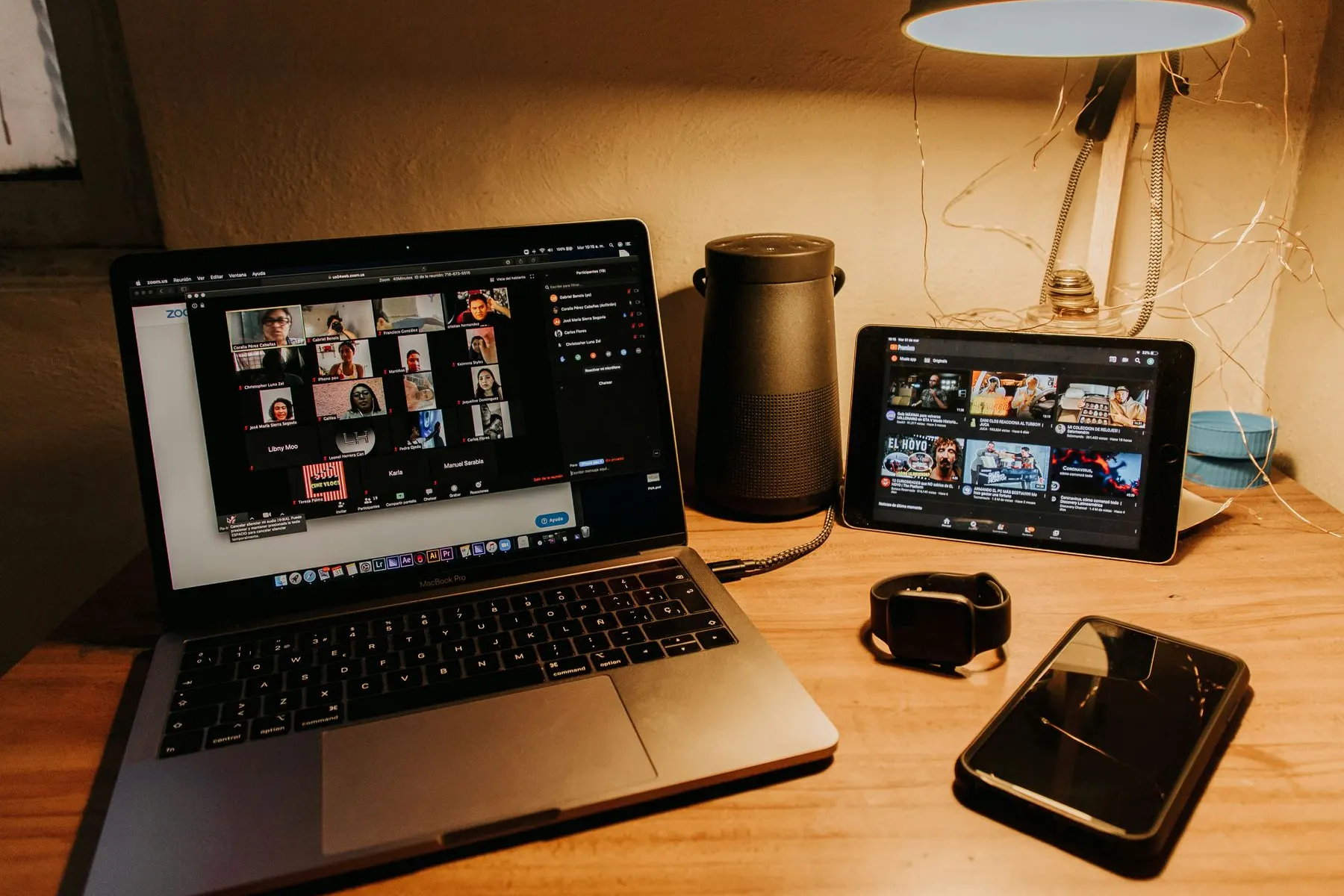 A laptop on a desk showing a video call full of faces