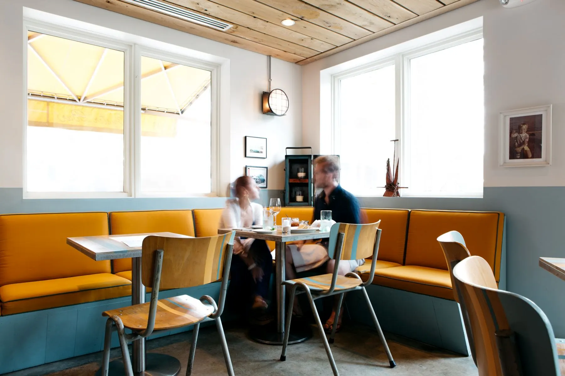 Two people talking at a cafe table by a sunny window